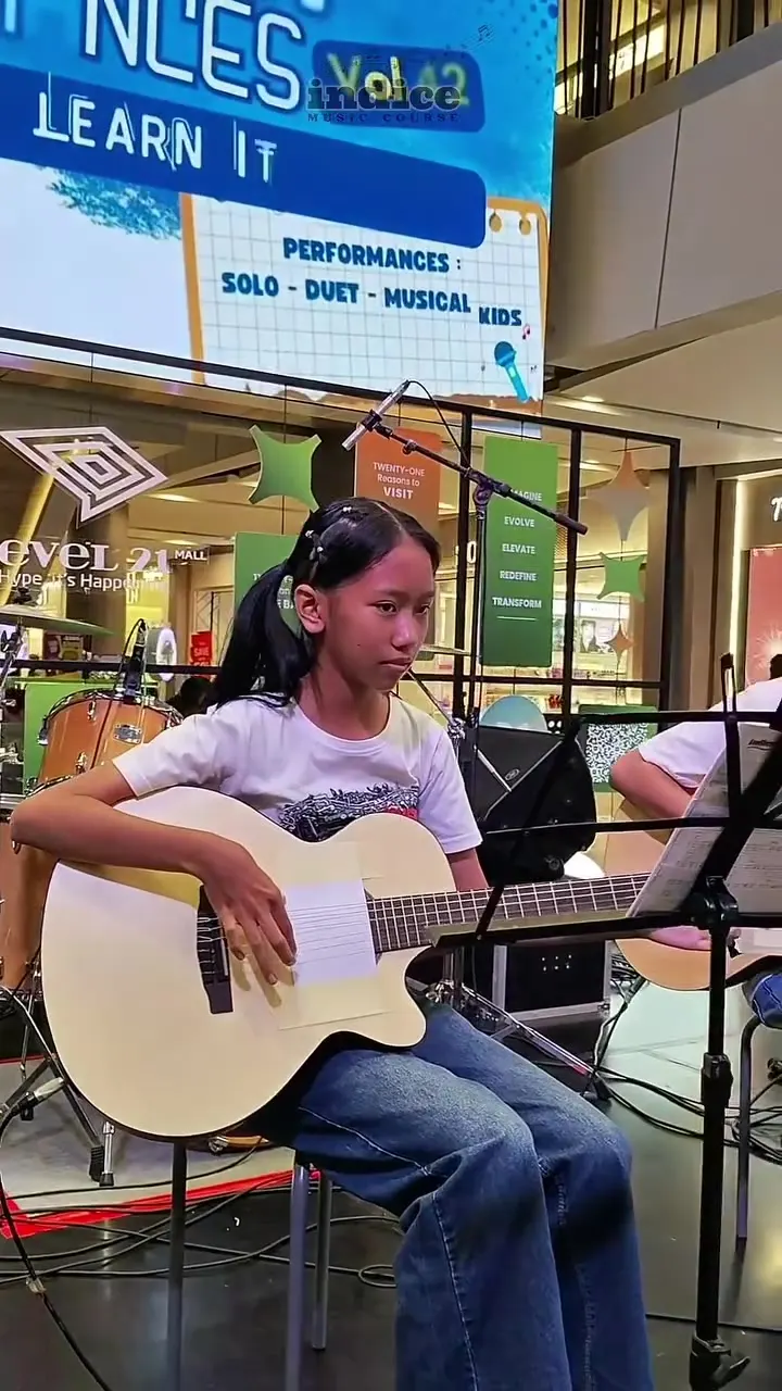 Murid gitar Indice memainkan gitar akustik di panggung Student Performances