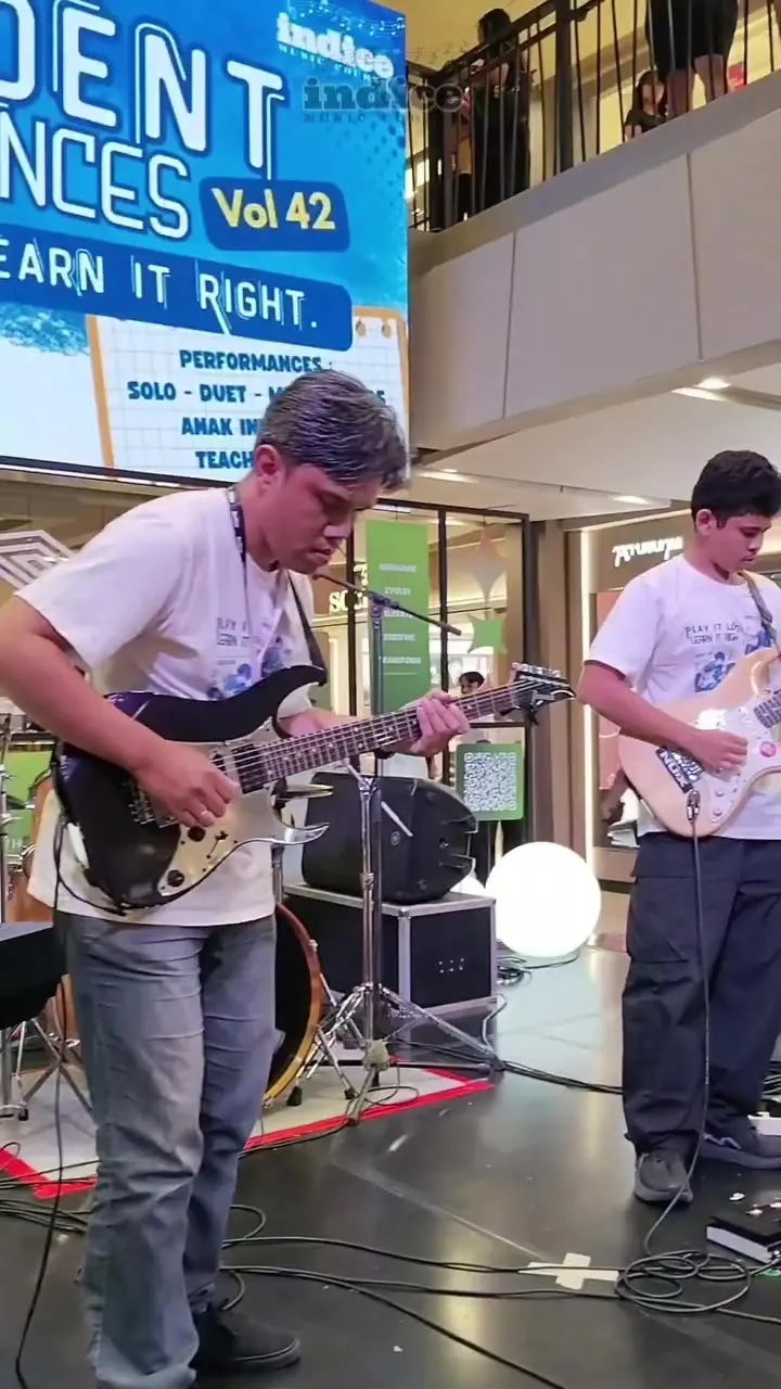 Guru dan murid bermain gitar elektrik di Teacher's Band